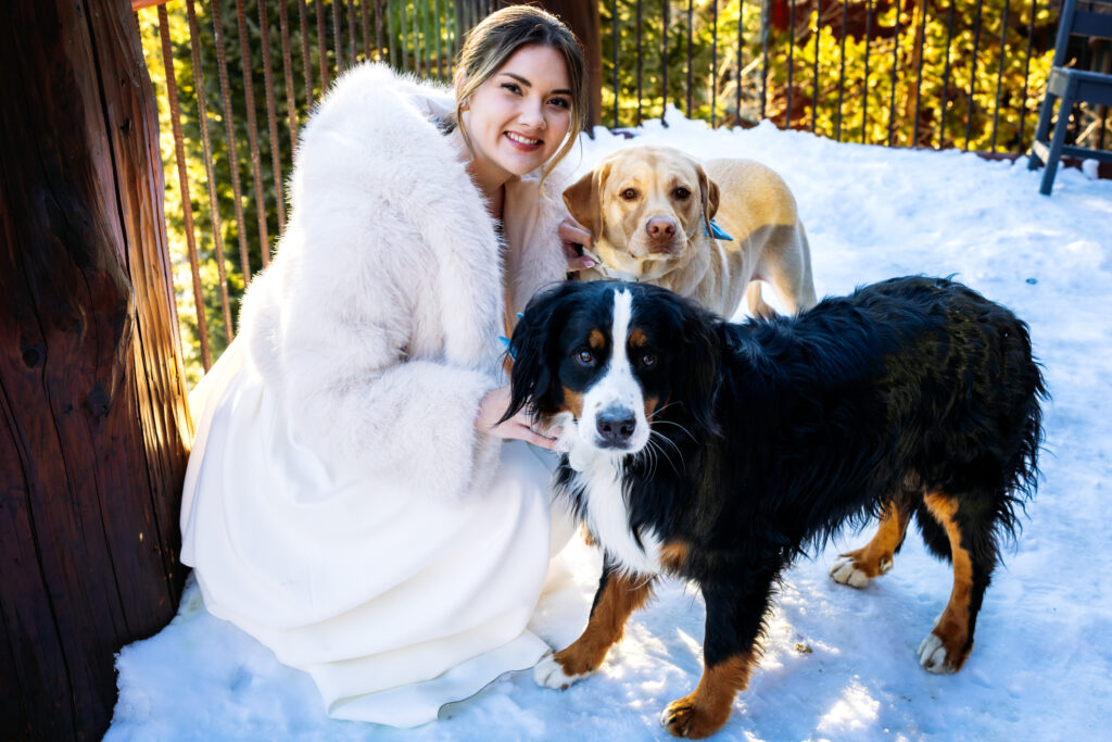 The bride and her two dogs pose for a portrait on the patio in the snow after her Breckenridge Elopement.