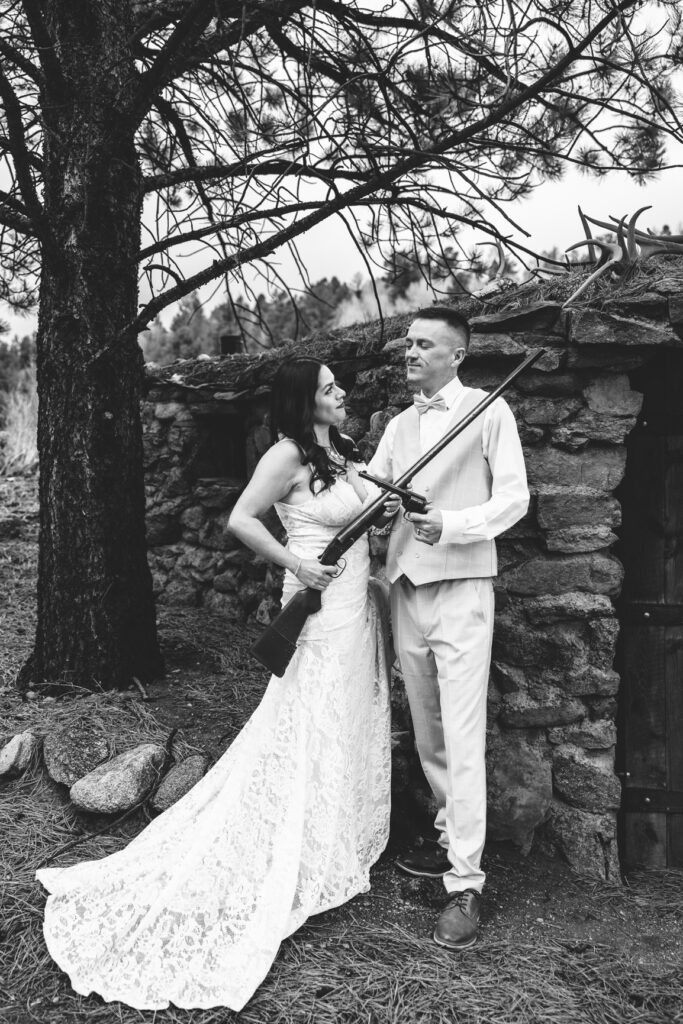 Couple posing with a family heirloom rifle during their Colorado ranch elopement.