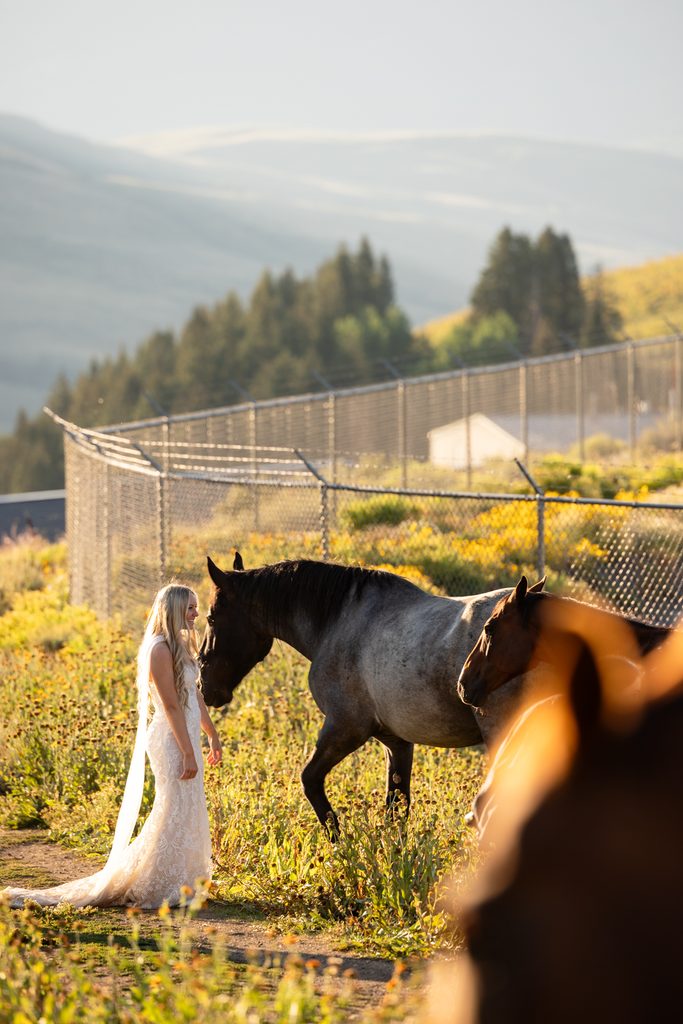 bride walks with horses during adventurous horse elopement in crested butte