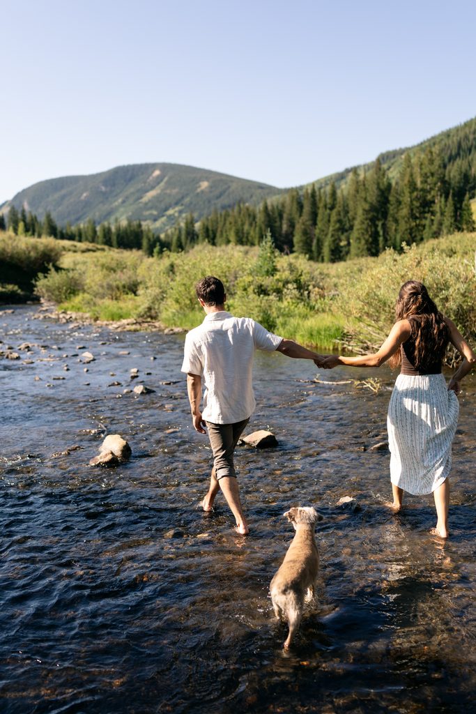 bride and groom explore river with their dog at sunrise Crested Butte elopement